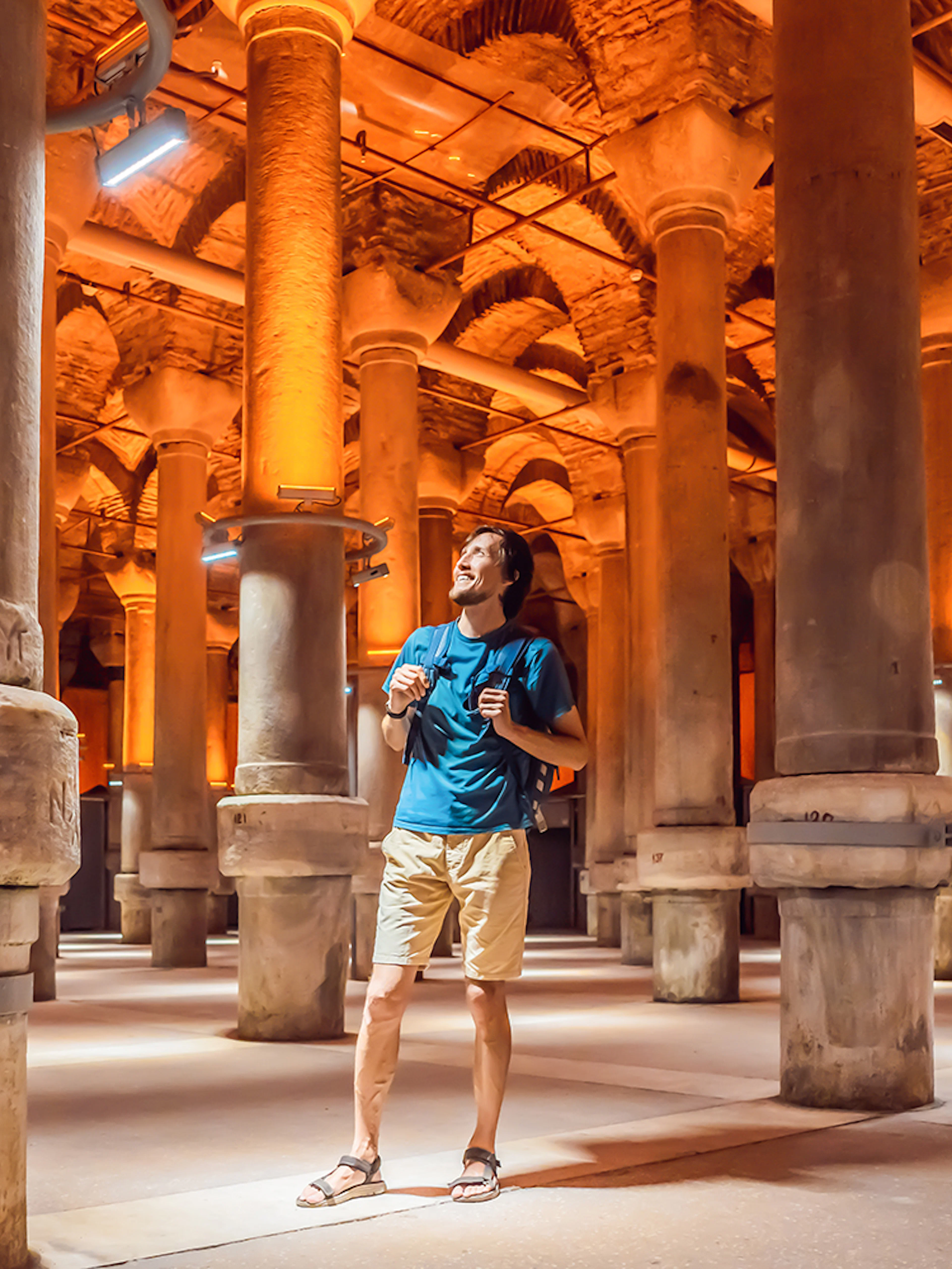 Tourist exploring the ancient columns of the Basilica Cistern in Istanbul.