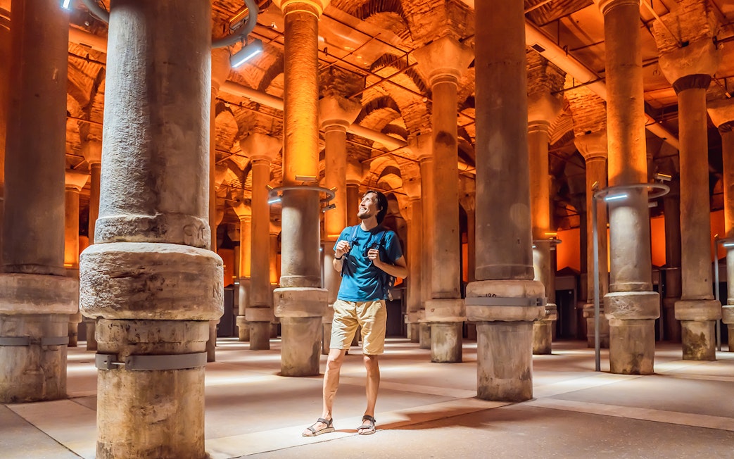 Tourist exploring the ancient columns of the Basilica Cistern in Istanbul.