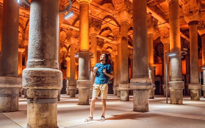 Tourist exploring the ancient columns of the Basilica Cistern in Istanbul.
