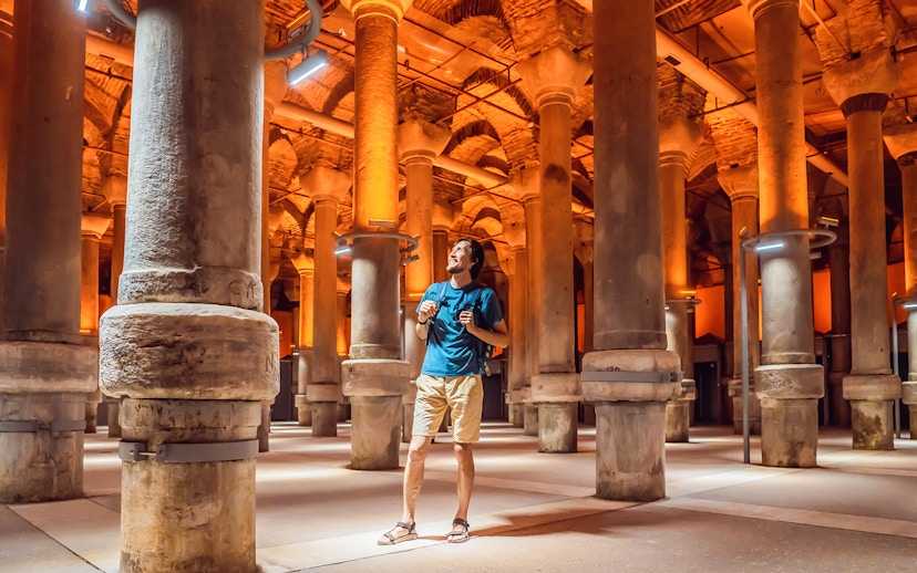 Tourist exploring the ancient columns of the Basilica Cistern in Istanbul.