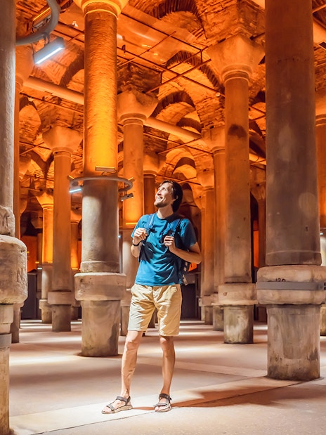 Tourist exploring the ancient columns of the Basilica Cistern in Istanbul.