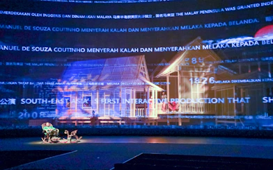 Interactive display of a traditional Kampung scene with historical text projections.