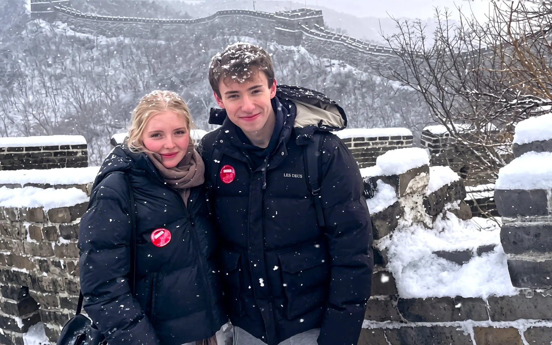 Couple standing on snow-covered Mutianyu Great Wall during bus tour.