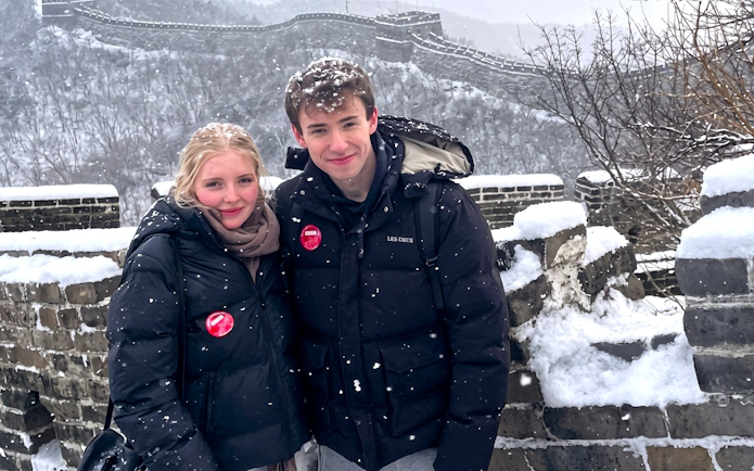 Couple standing on snow-covered Mutianyu Great Wall during bus tour.