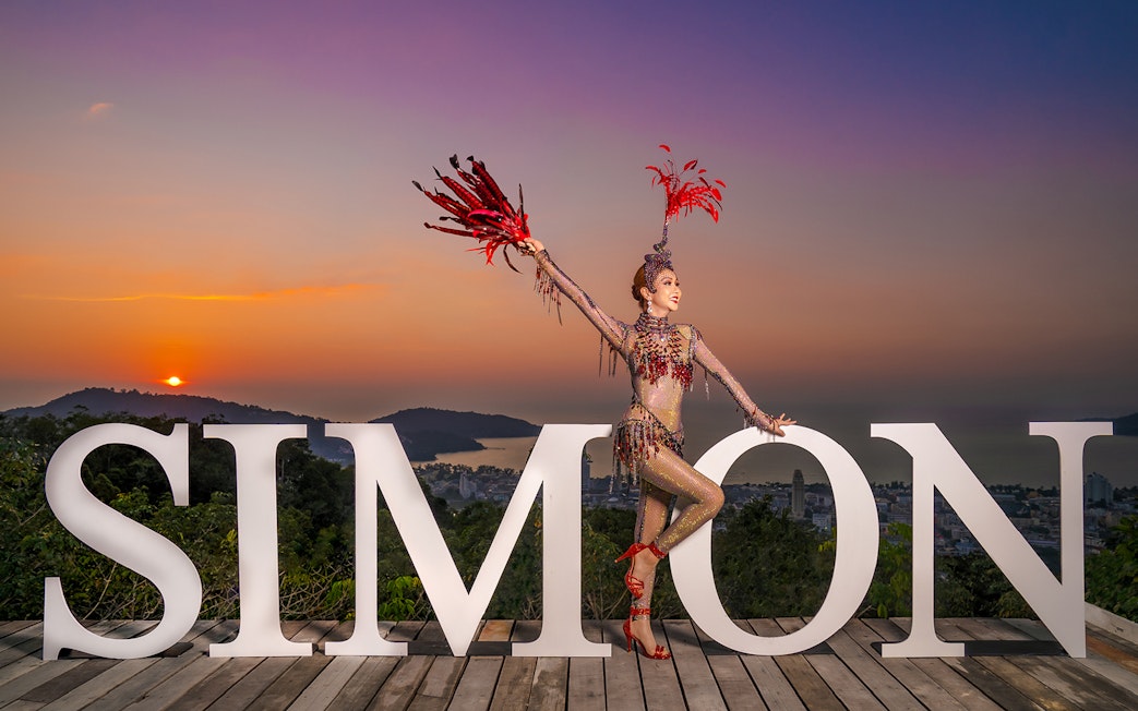 Performer in costume at Simon Cabaret Show with sunset backdrop in Phuket.