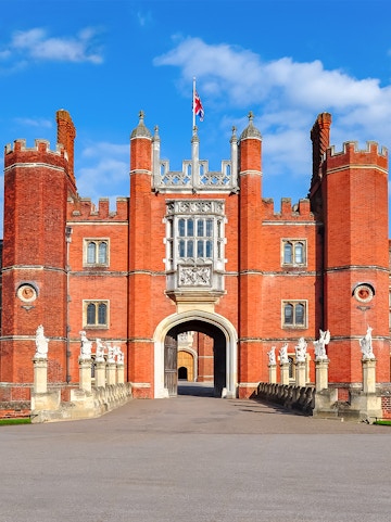 Hampton Court Palace entrance with red brick towers and Union Jack flag, London.