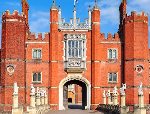 Hampton Court Palace entrance with red brick towers and Union Jack flag, London.