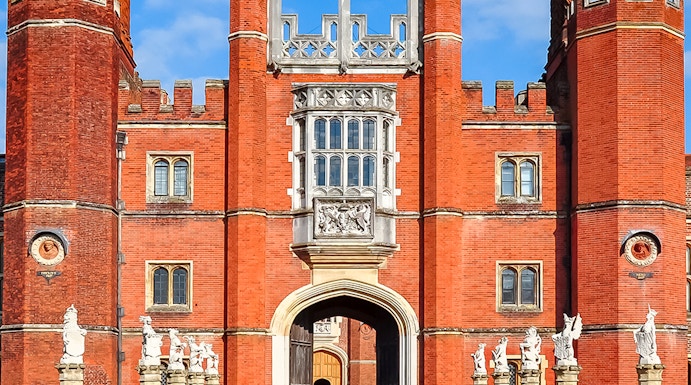 Hampton Court Palace entrance with red brick towers and Union Jack flag, London.
