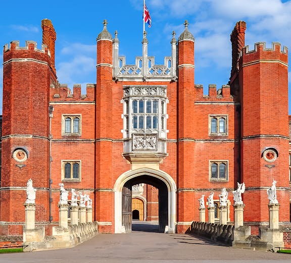 Hampton Court Palace entrance with red brick towers and Union Jack flag, London.