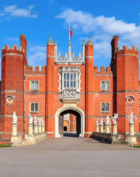 Hampton Court Palace entrance with red brick towers and Union Jack flag, London.