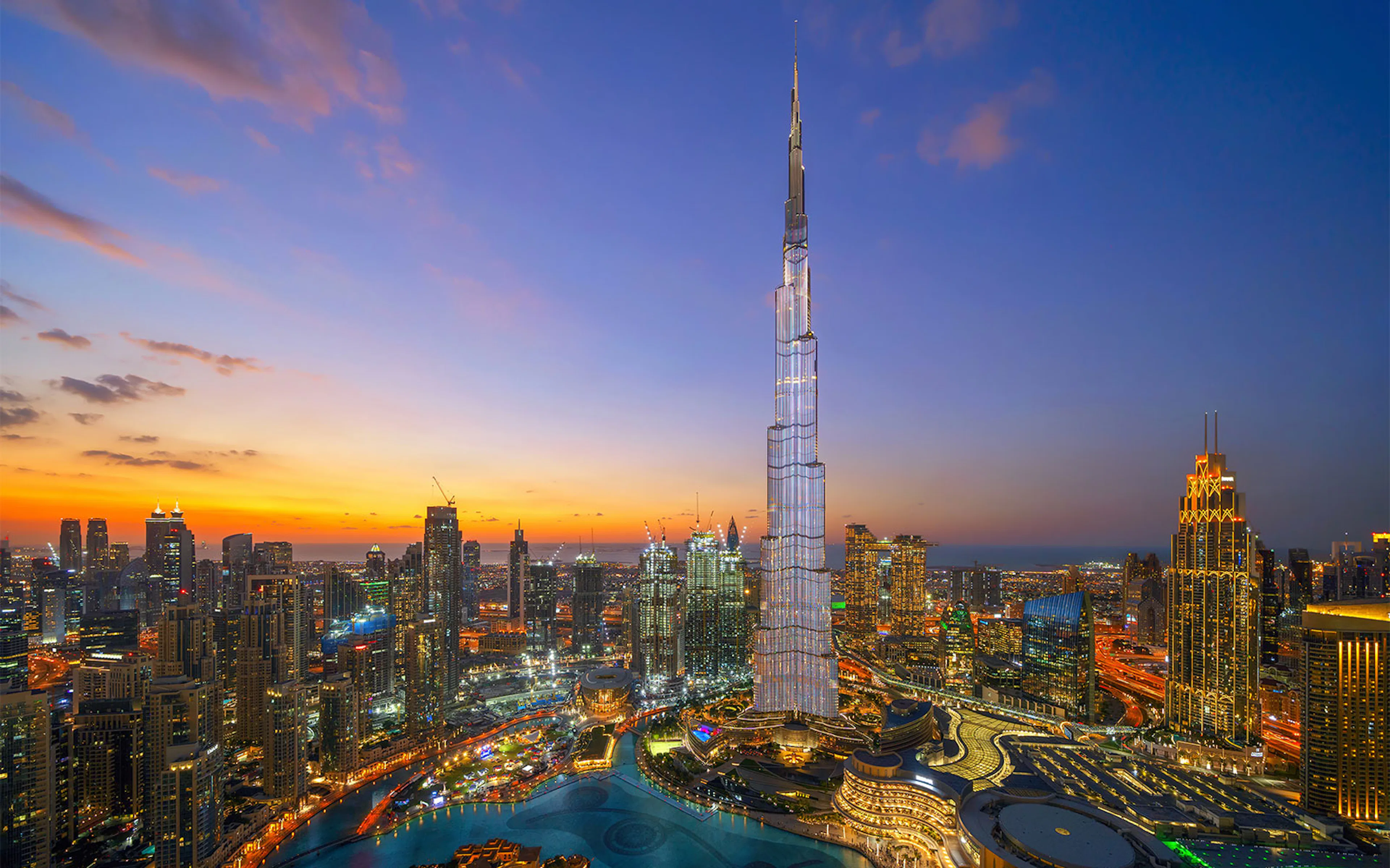 Aerial view of Burj Khalifa in Dubai at sunset with city skyline.