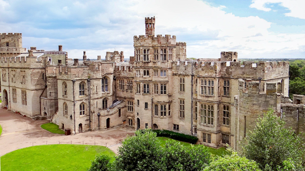 Warwick Castle exterior with stone towers and lush green grounds.