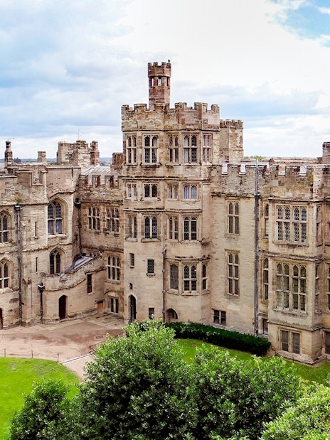 Warwick Castle exterior with stone towers and lush green grounds.