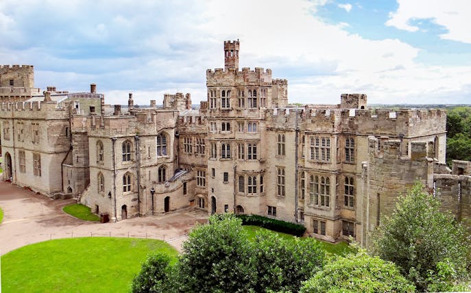 Warwick Castle exterior with stone towers and lush green grounds.
