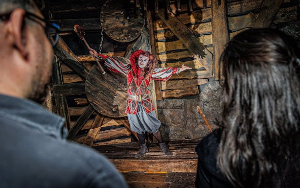Performer in medieval costume at Berlin Dungeon attraction.