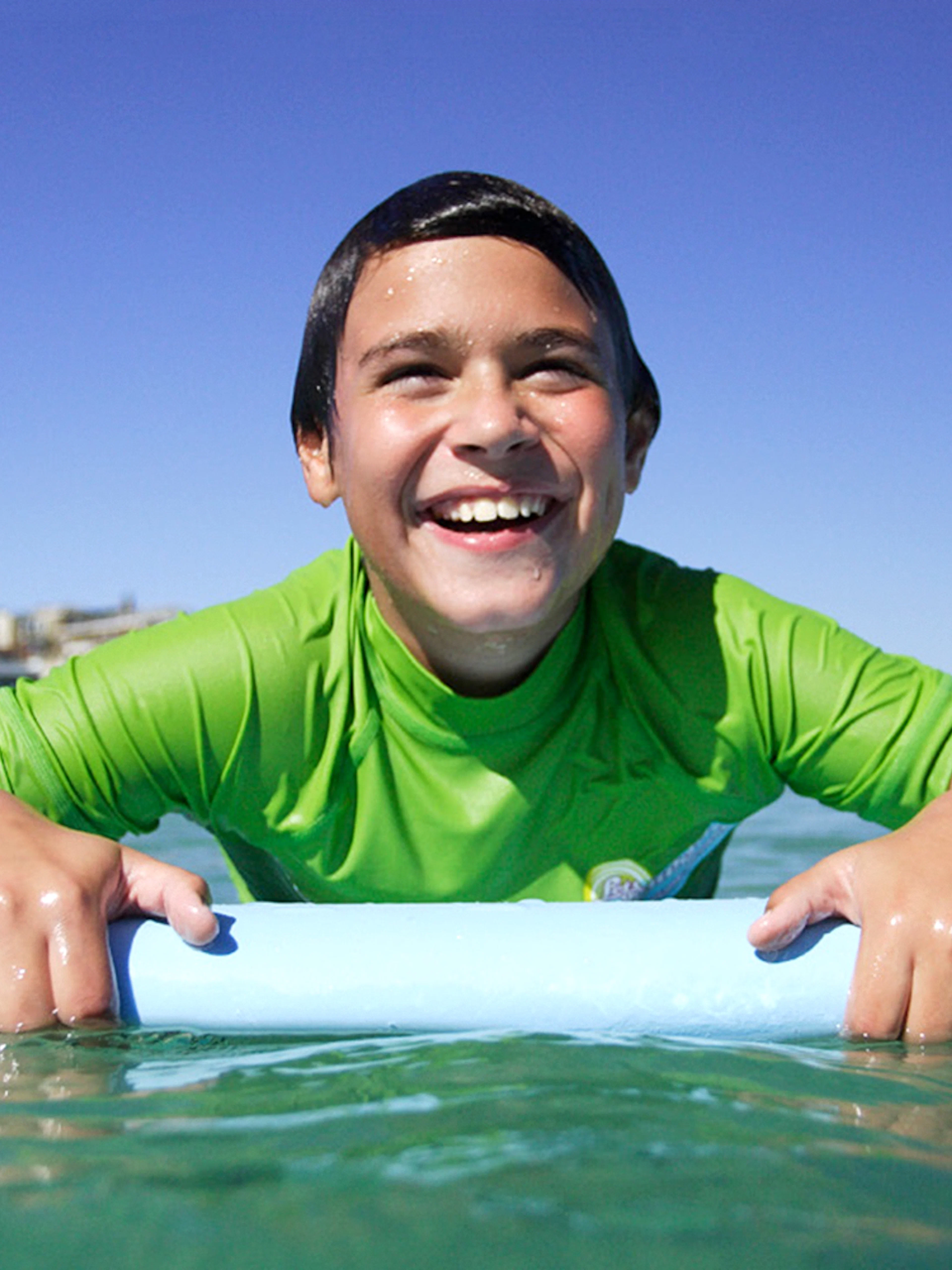 Child enjoying surf lesson at Bondi Beach, holding a surfboard in the water.