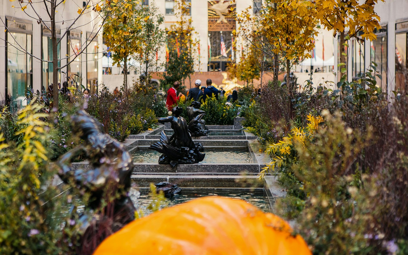 Rockefeller Center fountain with autumn foliage and sculptures in New York City.