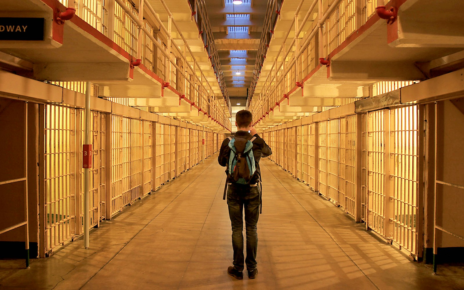 Visitor exploring Alcatraz prison cell block at night.