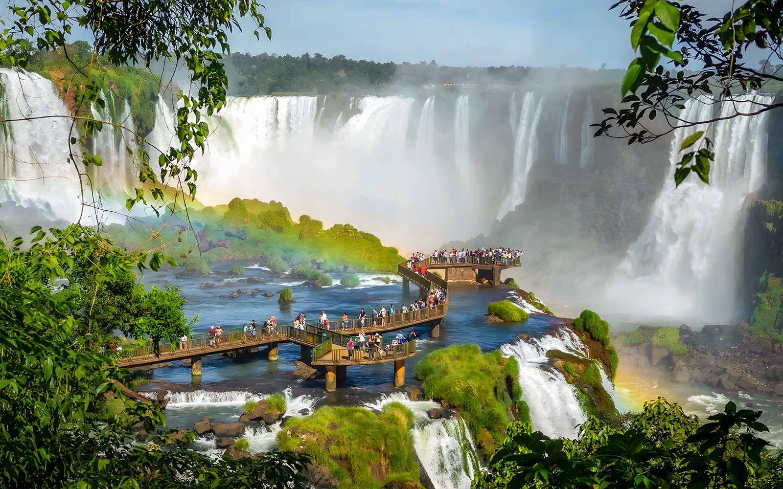 Tourists on viewing platform at Iguazú Falls, Brazilian side, with waterfalls in background.