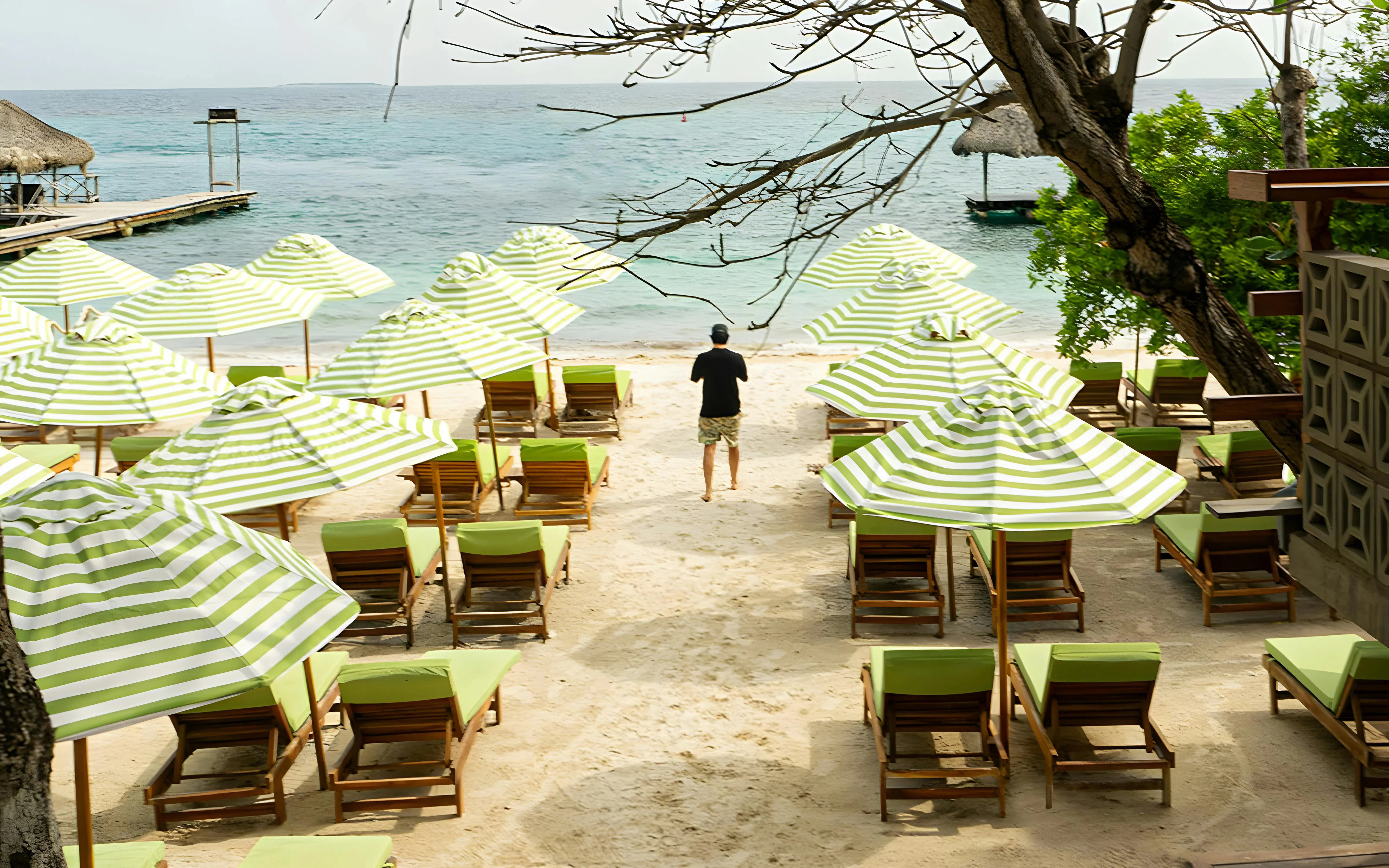 Beach chairs and striped umbrellas on a sandy shore in Rosario Islands, near Cartagena, Colombia.
