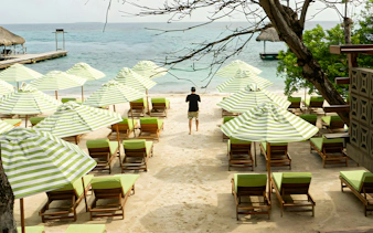Beach chairs and striped umbrellas on a sandy shore in Rosario Islands, near Cartagena, Colombia.