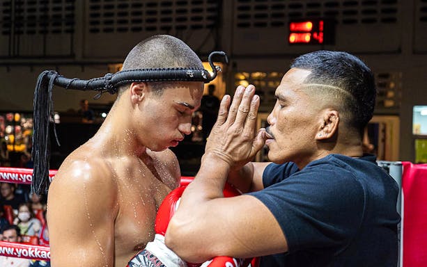 Muay Thai fighter and trainer performing pre-fight ritual at Patong Boxing Stadium.