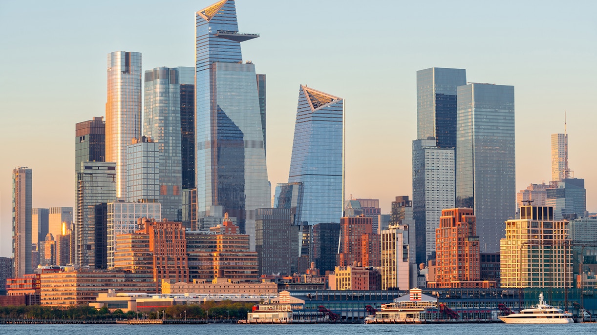 Hudson River view with New York City skyline and Statue of Liberty in the distance.