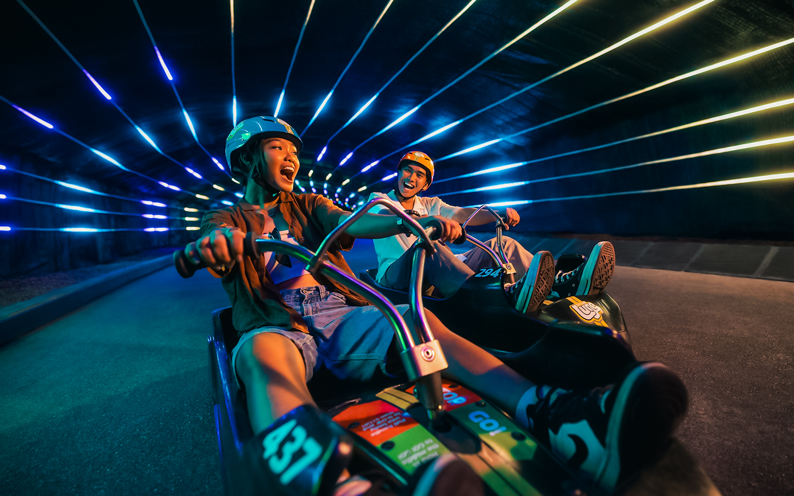 Friends enjoying night luge ride in illuminated tunnel, Singapore.