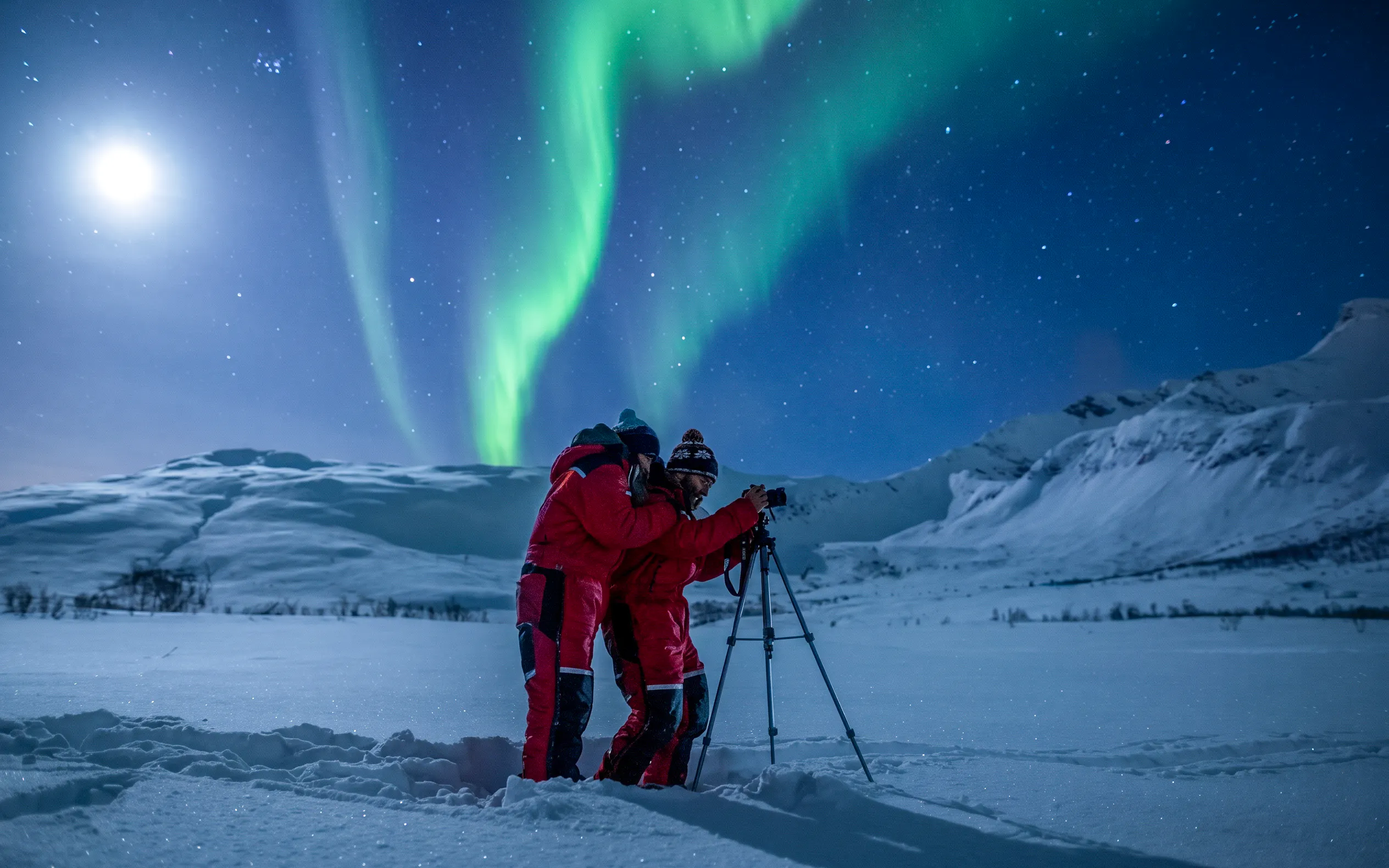 Photographers capturing Northern Lights in Tromso snowy landscape.