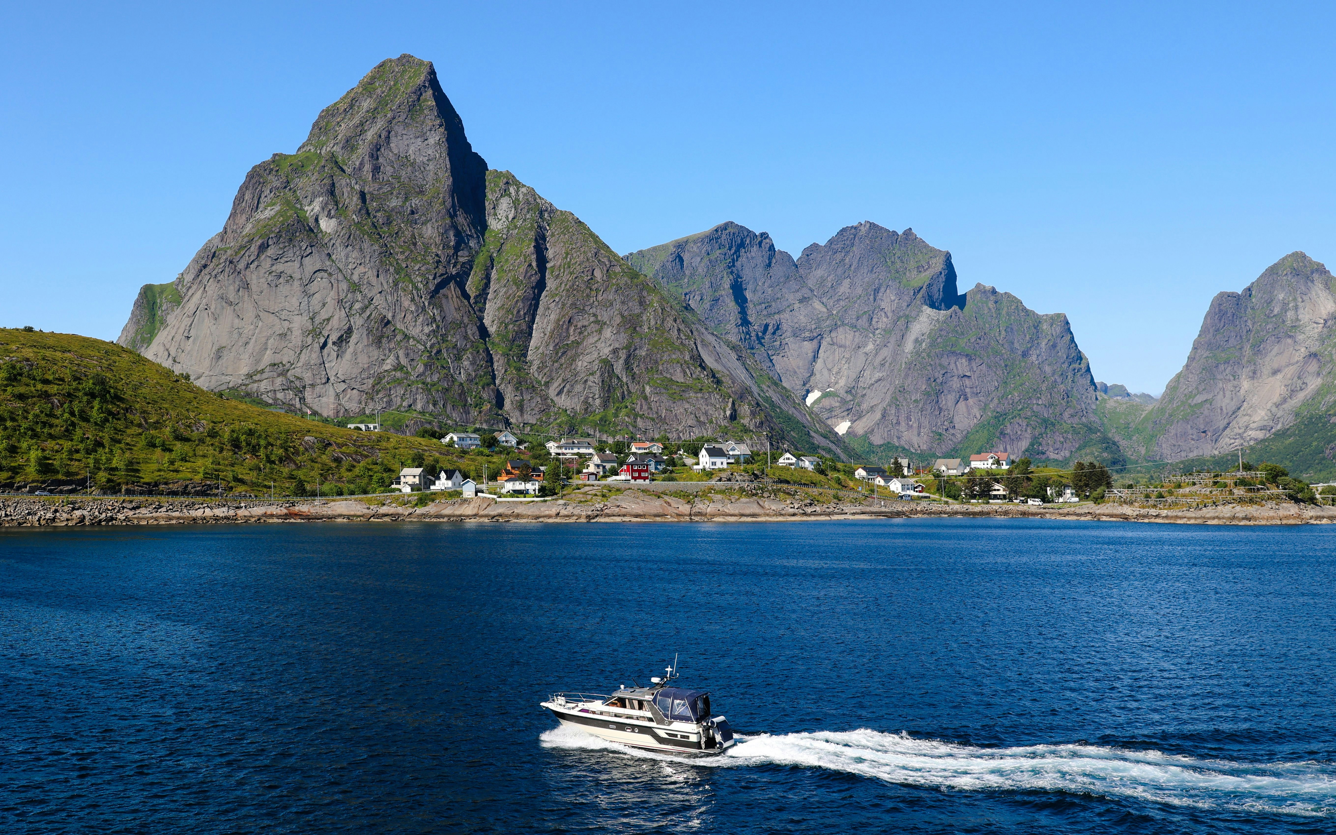 Boat cruising near mountain scenery on the coast of Lofoten, Norway.