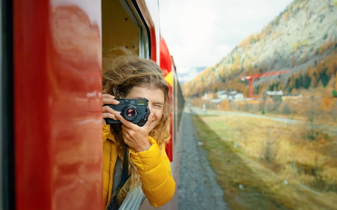 Passenger photographing scenery from Bernina train window in Switzerland.