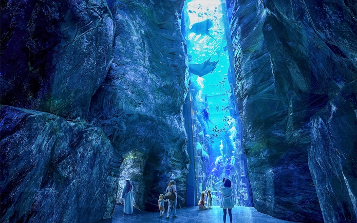 Underwater aquarium tunnel with visitors observing marine life and divers.