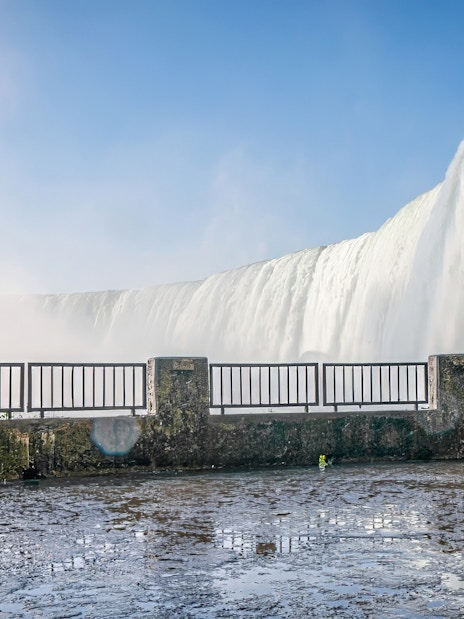 Person in yellow poncho viewing Niagara Falls from observation deck.