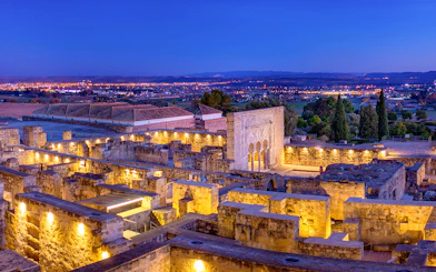 Illuminated ruins of Medina Azahara with archways and columns at dusk, Córdoba, Spain.