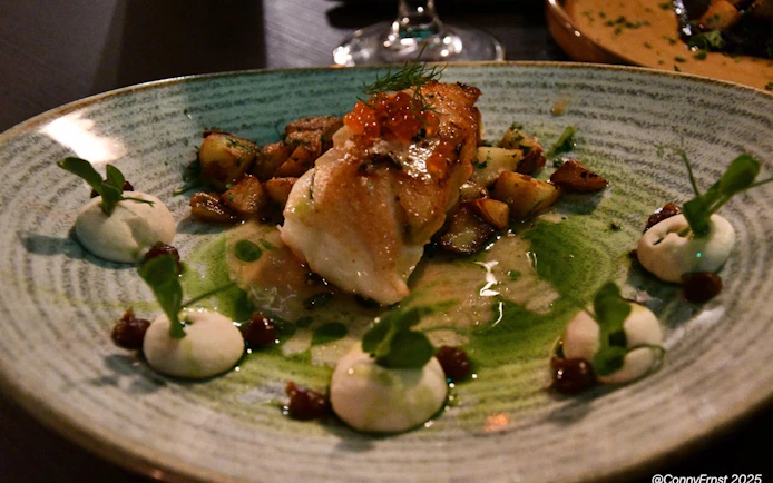 Traditional Icelandic dish with fish, potatoes, and garnish in an exclusive restaurant setting.