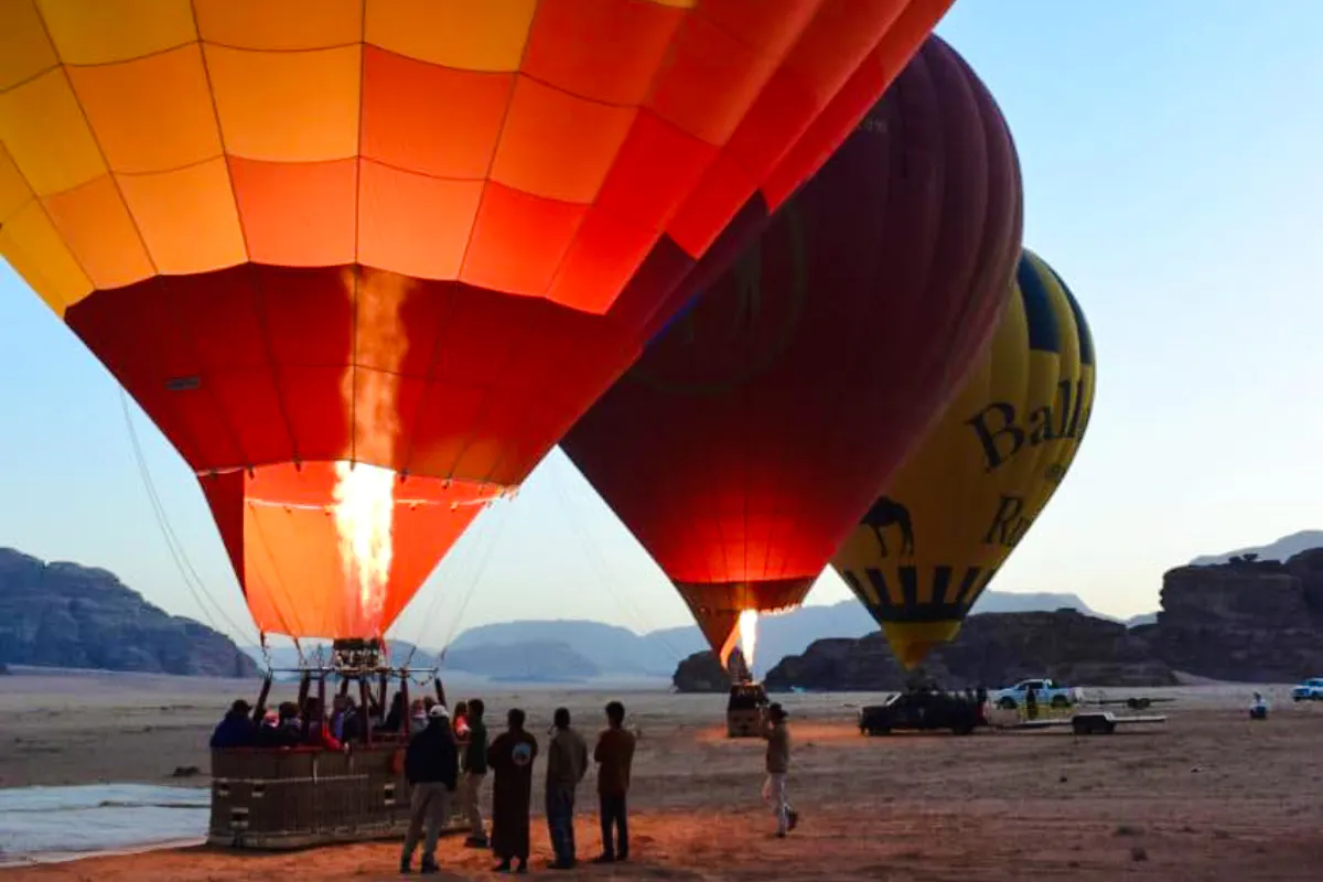 Hot air balloons preparing for flight at sunrise in Wadi Rum desert.