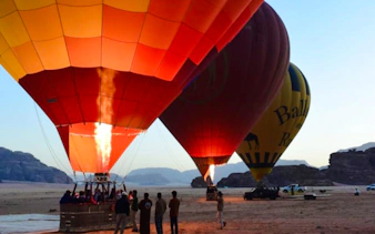 Hot air balloons preparing for flight at sunrise in Wadi Rum desert.