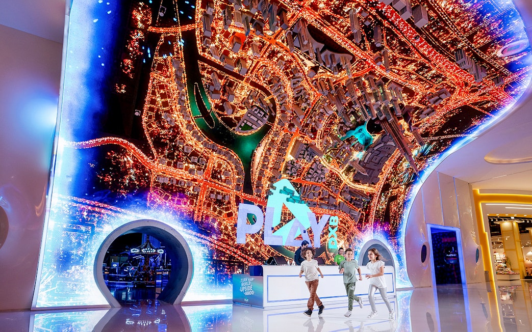Play DXB entrance with children running, featuring a vibrant cityscape display.