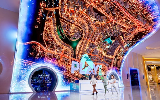 Play DXB entrance with children running, featuring a vibrant cityscape display.