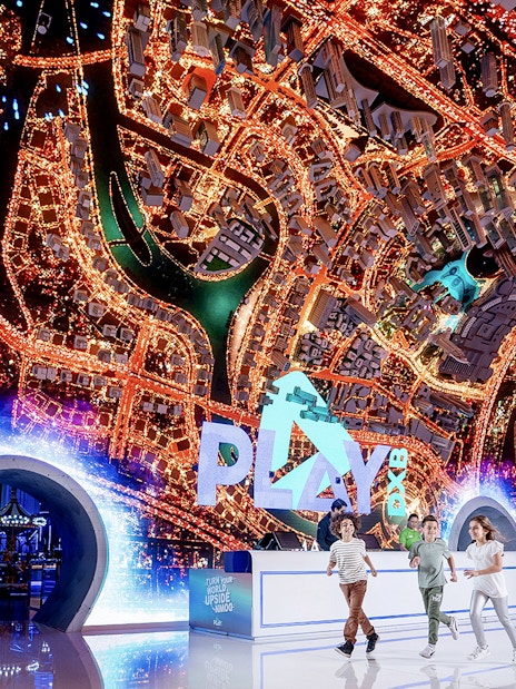 Play DXB entrance with children running, featuring a vibrant cityscape display.