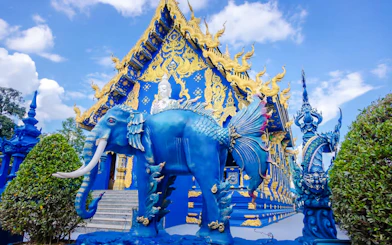 Blue Temple (Wat Rong Sua Ten) with intricate blue and gold designs and mythical creature statues in Chiang Rai, Thailand.
