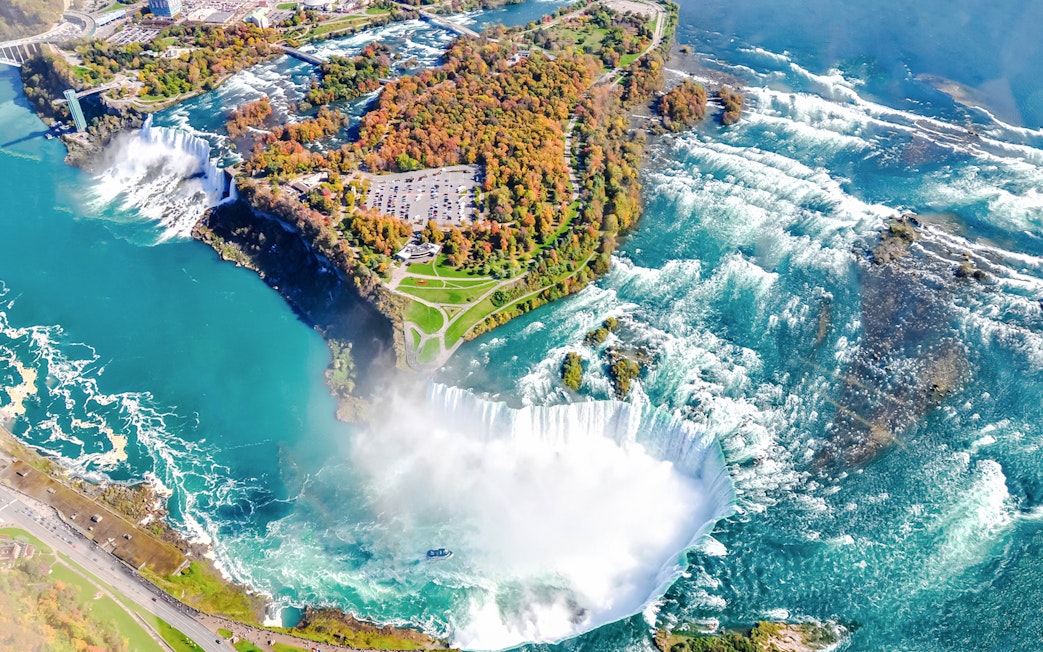 Aerial view of Niagara Falls with surrounding greenery and river.