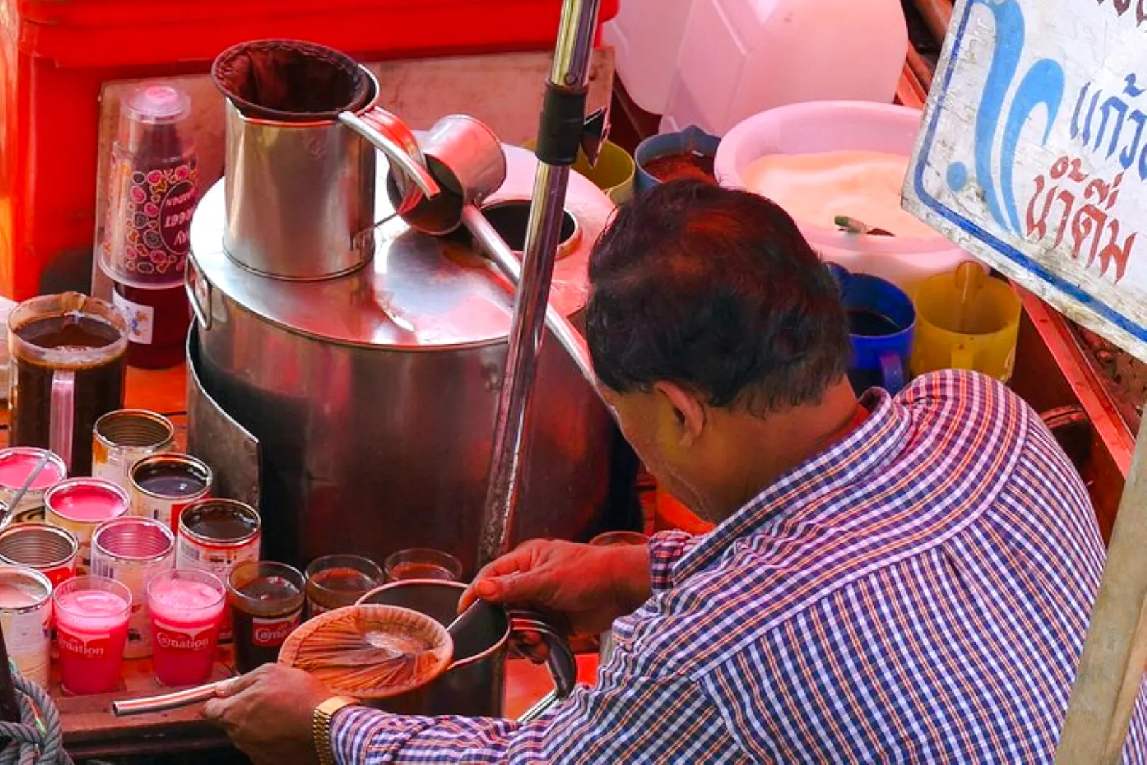 Vendor preparing traditional coffee at Amphawa Floating Market, Thailand.