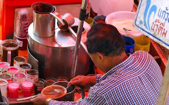 Vendor preparing traditional coffee at Amphawa Floating Market, Thailand.
