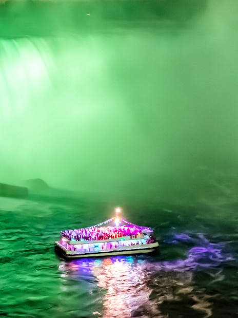 Boat illuminated at night near Niagara Falls during evening tour from Toronto.