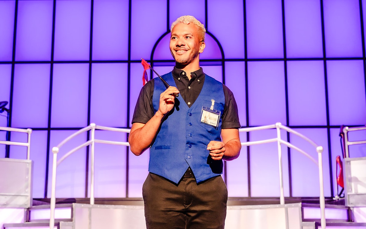 Performer on stage during Titanique West End show, holding a small flag.