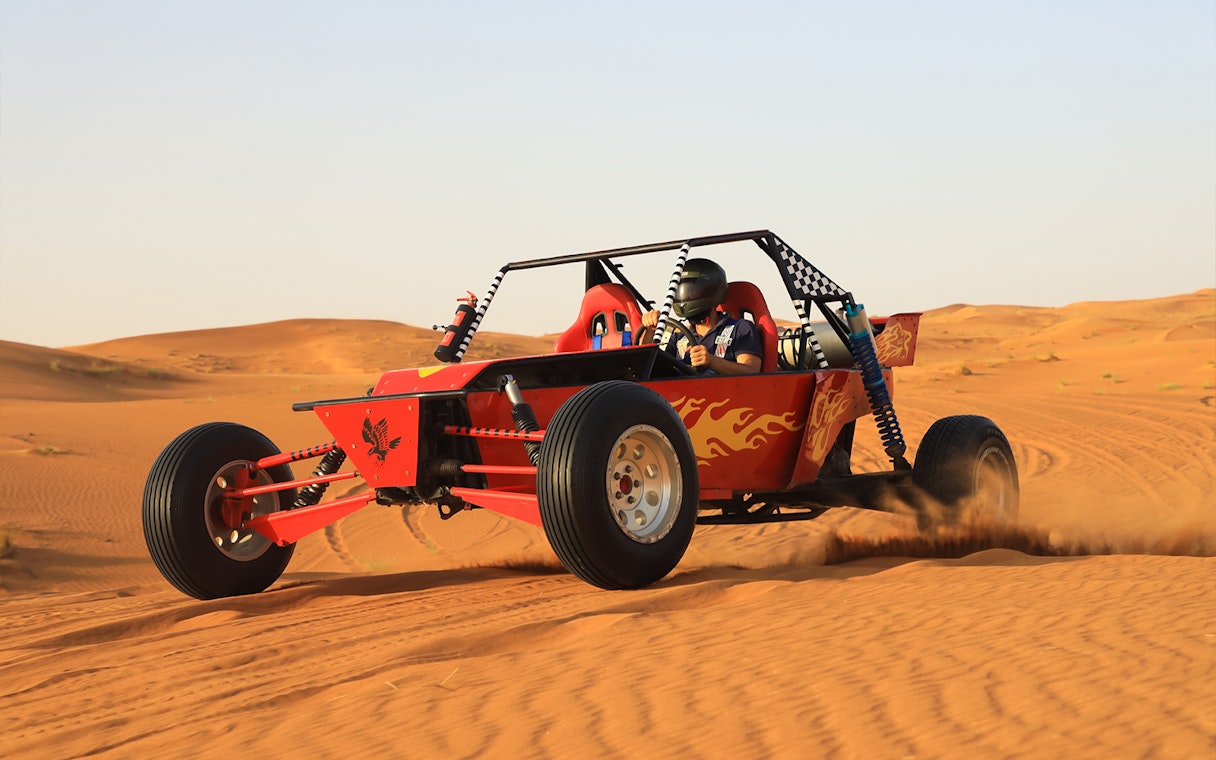 Dune buggy driving through Dubai's Red Dunes desert.