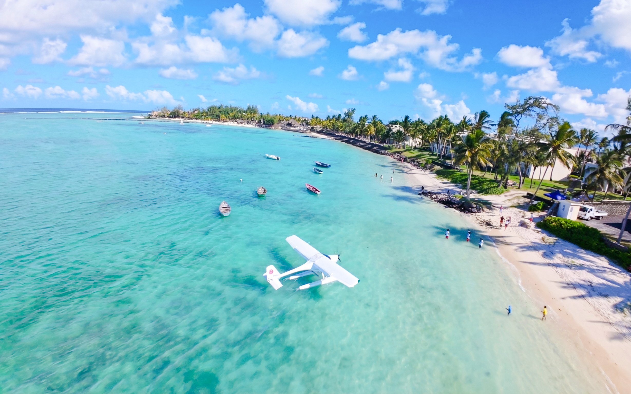 Seaplane landing on turquoise waters near a sandy beach in Mauritius.