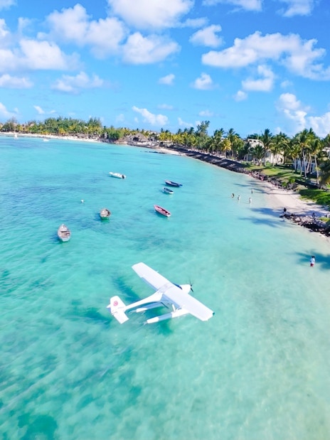 Seaplane landing on turquoise waters near a sandy beach in Mauritius.