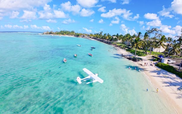 Seaplane landing on turquoise waters near a sandy beach in Mauritius.